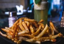 potato fries on black ceramic plate on top of wooden table