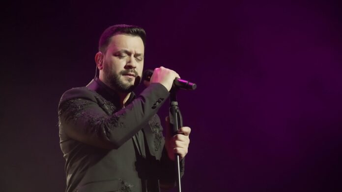 Lucas Sugo cantando en el escenario con los ojos cerrados